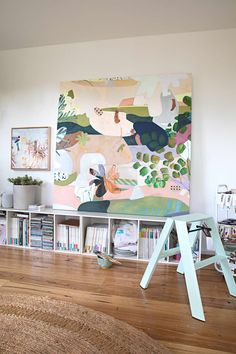 a living room with bookshelves and a painting on the wall