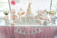 a table topped with lots of desserts and cupcakes next to a window