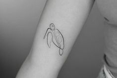 a woman's arm with a small tattoo of a turtle on the left forearm