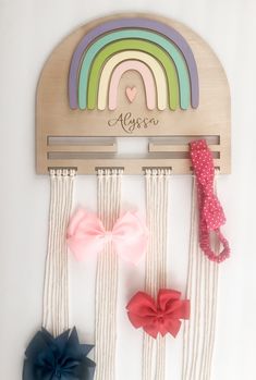 three little bows are hanging on the wall in front of a personalized name sign