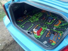 the trunk area of a blue car with a toy town on it's floor