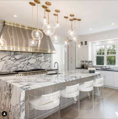 a large kitchen with marble counter tops and white chairs in front of an island that is surrounded by hanging lights