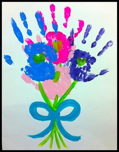 handprints on the paper with flowers in a vase and blue ribbon tied around it