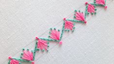 a close up of a piece of fabric with pink and green beads