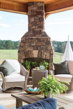 an outdoor living room with stone fireplace and furniture