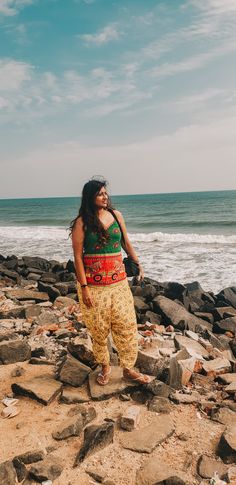 a woman standing on rocks near the ocean