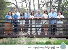 a group of people standing on top of a bridge next to each other in front of trees