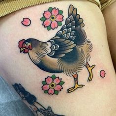 a woman's thigh with a rooster and flowers on her side, tattoo style