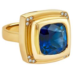 Introducing a blend of opulence: the Chocolate Gold Blue Sapphire Ring, a luxurious masterpiece exuding elegance and allure. Appropriately named "Sapphire Temptation," this statement gold ring features mesmerizing blue tones that mirror the richness of the finest treats. Experience guilt-free splendor as this exquisite blue sapphire ring adorns your finger with unparalleled sophistication. The cushion-cut blue sapphire, nestled within the lavish contours of yellow gold, radiates pure magnificence. Enhanced by sparkling white diamonds at each corner, its charm reaches dazzling new heights. Whether as a personal indulgence or a treasured gift, this ring embodies the essence of decadence and refinement. The striking Chocolate Gold Blue Sapphire Ring effortlessly takes center stage. With its d Luxury Gold Sapphire Ring In Recycled Gold, Luxury Faceted Sapphire Ring In Yellow Gold, Luxury Yellow Gold Elegant Sapphire Ring, Luxury Yellow Gold Rings With Lab-created Sapphire, Luxury Gold Rings With Lab-created Sapphire, Gold Blue Sapphire Ring, Statement Gold Ring, Chocolate Gold, Deep Royal Blue