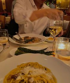 a person sitting at a table with plates of food and wine