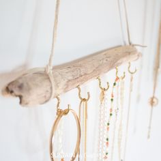 a piece of driftwood hanging from a wall with beads and chains attached to it