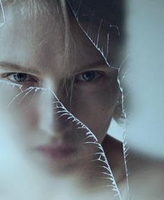 a woman's face is seen through the torn glass in this artistic photo taken by an unknown photographer