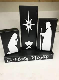 three black and white nativity blocks with the silhouettes of two people holding a baby jesus