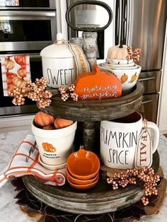 a cake stand with pumpkins and coffee mugs sitting on it's sides