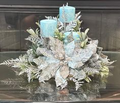 a glass table topped with blue candles and snowflakes covered in frosted leaves