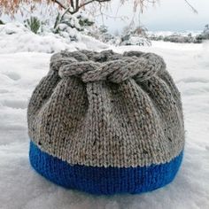 a knitted beanie sitting in the snow with a knot on it's side