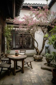 a table and chairs in front of a tree with pink flowers