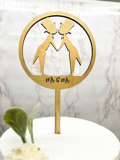 a wooden cake topper with two people holding hands