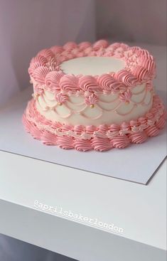 a pink and white cake sitting on top of a table