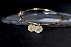 "A tiny 9mm disc, engraved with your short and sweet message, floats freely on a handmade clasp bangle. The bangle is made to order in the size you choose, and textured for lots of extra sparkle.   METAL & PERSONALIZATION OPTIONS   Use the Personalization field to indicate your engraving text. If no font is noted, Font B will be used.   SIZE OPTIONS  This bracelet has a circular shape and opens, allowing for a closer fit than a traditional closed bangle. The sizes below reflect the inside circum Minimalist Hand Stamped Jewelry For Bridesmaids, Gold Round Nickel-free Name Bracelet, Gold Nickel-free Round Name Bracelet, Adjustable 14k Gold Charm Bracelet, Minimalist Personalized 14k Gold Charm Bracelet, Personalized Minimalist 14k Gold Charm Bracelet, Personalized Yellow Gold Bracelets, Minimalist Engraved Charm Bracelet As Personalized Gift, Minimalist Engraved Jewelry For Bridesmaid Gift