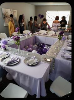 a group of people standing around a table with purple and silver decorations