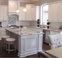 a large kitchen with white cabinets and marble counter tops, along with an island in the middle