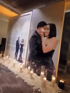 a man and woman are hugging in front of candles on the table with pictures behind them