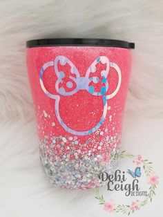 a pink and blue minnie mouse tumbler cup with glitter on the side, sitting on a white furnishing