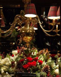 a chandelier decorated with christmas flowers and pine cones