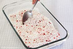 a person scooping red and white sprinkles into a glass dish with a spoon