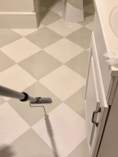 a person is using a vacuum to clean the floor in a bathroom with checkered tile