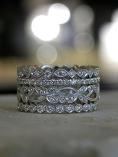 two wedding bands with diamonds on them sitting on a table in front of some blurry lights