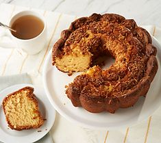 a bundt cake sitting on top of a white plate next to a cup of tea