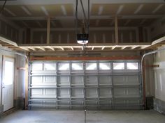 an empty garage with no one inside or outside the door and some lights hanging from the ceiling