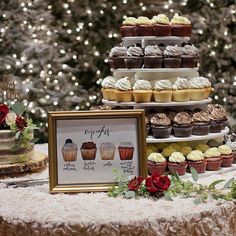 a table topped with lots of cupcakes next to a cake stand filled with cakes