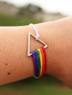 a woman's arm with a rainbow bracelet on it and a silver triangle charm