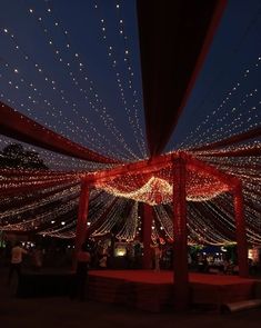 the inside of a tent with lights all over it and people walking around in the background