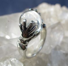 This is a Hand Cast Sterling Silver Ring with a unique "Crystal Ball" design. It is set with a 10 mm Natural Quartz Crystal Ball. This original design has two hands holding the crystal ball. Unique ring, surely will be noticed everywhere you go. The ring is about 7/16 inch wide on top and tapers to a plain shank in the back. It is 7/16 inch tall. Truly Magical ! This ring is made in a size 7 1/4. I will wrap the ring in a gift box and mail in a small box within 1-2 days of purchase, usually one. First Class postage with tracking is FREE to the U.S. Two Hands Holding, Crystal Ball Ring, Magical Crystal, Hands Holding, Ball Design, Rose Ring, Unique Ring, Hand Cast, Silver Roses