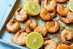 cooked shrimp with lemon wedges on a baking sheet