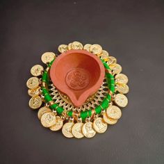 a bowl with coins around it on a black surface next to a red vase filled with green beads