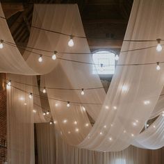 a room filled with lots of white drapes and string lights hanging from the ceiling