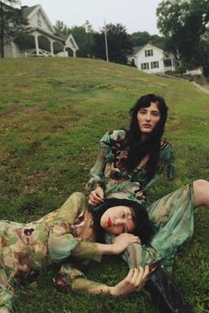 two women laying in the grass with their heads on each other