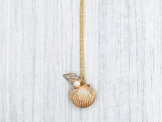 "A lovely and beautiful gold seashell locket necklace. It features a shining gold seashell along with white conch and pearl. The pearl is genuine Swarovski 6mm pearl. It suspends in a gold finished brass chain along with lobster claw clasp closure. The shell locket inside can hold pictures in both side 16mm x 14mm. It is a wonderful idea for gift giving or as a little treat for yourself. Your necklace will present in a gift box and tied with ribbon. Measurements and details: Length: 16\", 18\", Gold Pearl Necklace As Gift, Gold Shell Jewelry For Weddings, Gold Shell Necklaces For Weddings, Gold Shell Necklace For Wedding, Gold Shell Pearl Necklace, Shell-shaped Gold Jewelry For Wedding, Gold Shell With Pearl Charm For Gift, Gold Shell With Pearl Charm As Gift, Vintage Shell Gold Jewelry