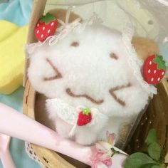 a white stuffed animal in a basket with strawberries on it's ears and eyes