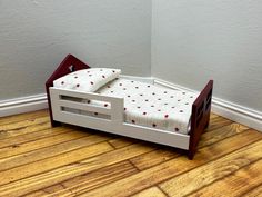 a wooden bed with red and white bedspread sitting on top of a hard wood floor