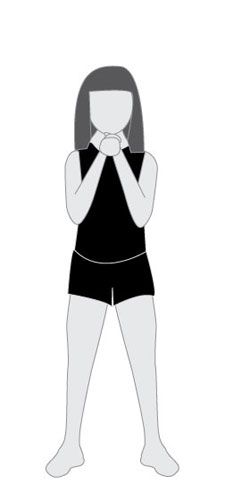 a woman standing with her hands folded in front of her face and wearing black shorts