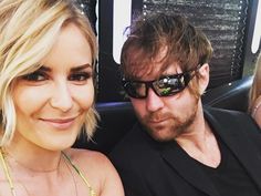 a man and woman sitting next to each other in front of a car with sunglasses on