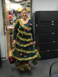 a woman wearing a christmas tree costume standing in an office cubicle with her hands on her hips