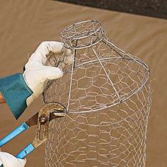 a person in white gloves is holding a pair of scissors near a wire cage with a blue handle