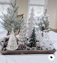 christmas trees are sitting on a tray with pine cones and snowflakes in them